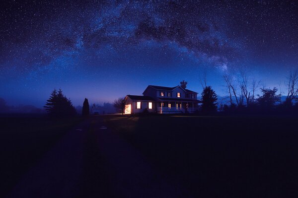 A house with burning windows and a starry night sky