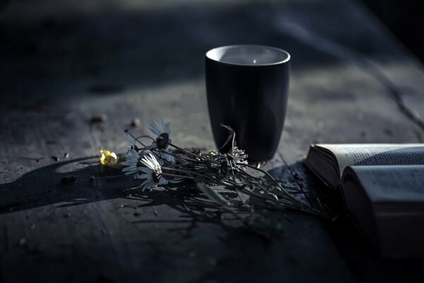 Fleurs avec une tasse sur une table avec un livre