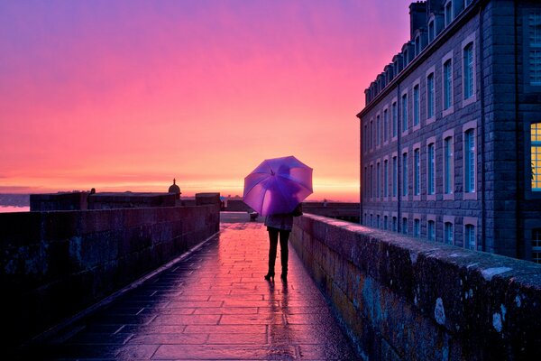 Fille sous un parapluie au milieu de la ville au coucher du soleil