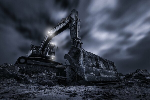 Excavator digs the ground against the background of dark clouds