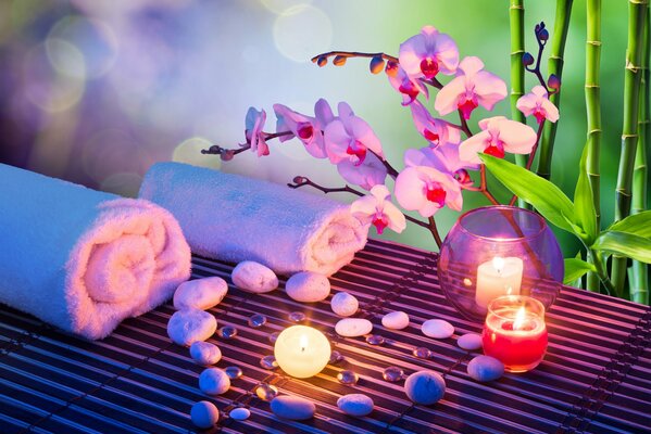 Ambiente de Spa, piedras en forma de corazón extendidas en la superficie, toallas enrolladas en un tubo y velas encendidas al lado