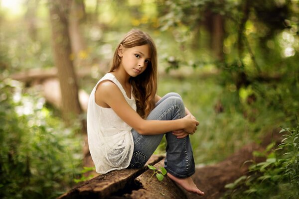 The girl is sitting in nature hugging her knees