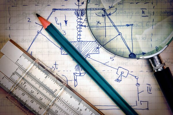 Règle logarithmique, crayon et loupe se trouvent sur le cahier