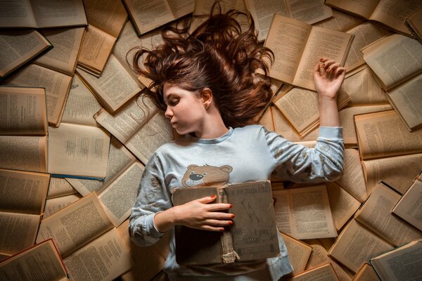Dziewczyna w piżamie śpi na książkach