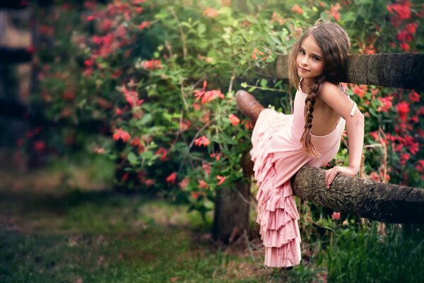 Una niña con una coleta en un vestido rosa sobre un fondo de flores