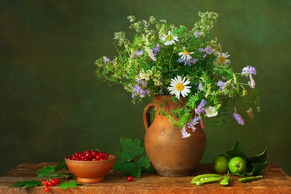 Nature morte sur la table est un pichet avec un bouquet de fleurs et autour des baies et des pommes