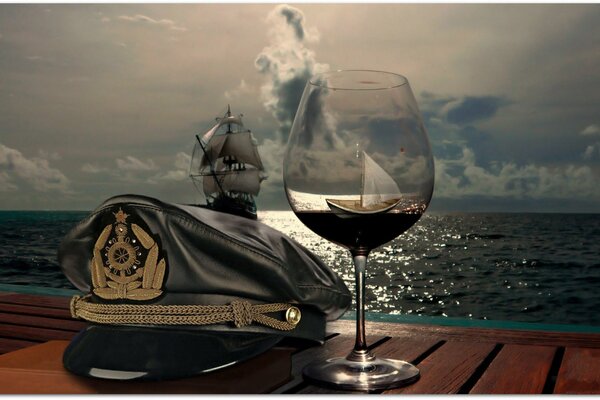 A cap and a glass on the background of a ship at sea