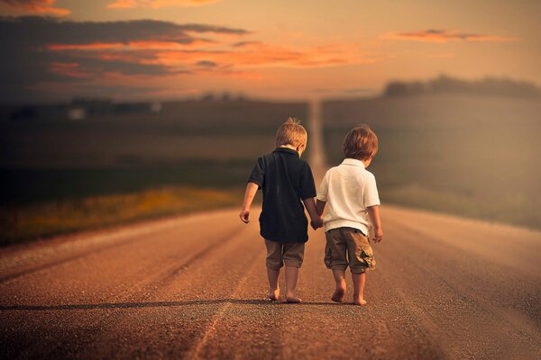Dwóch małych chłopców boso idzie pustą drogą