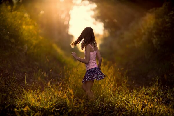 Naturaleza de la mañana, pintada con colores brillantes e iluminada por los brillantes rayos del sol. Una niña corriendo hacia la luz