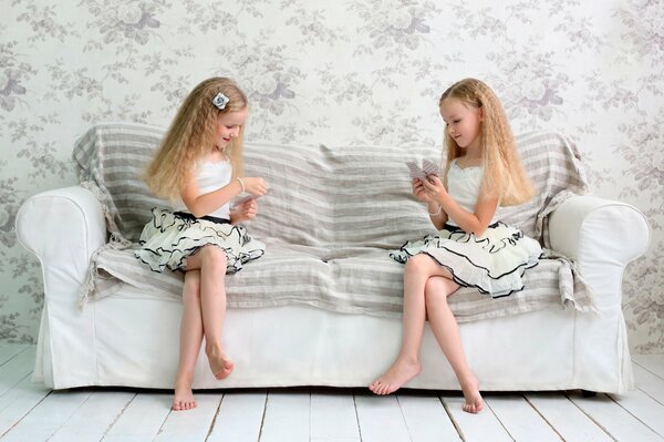 Two girls play cards on the couch