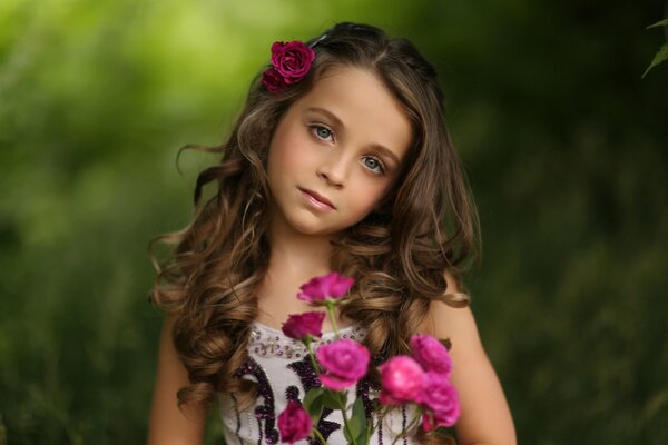 Retrato de una niña con rosas en el fondo del follaje