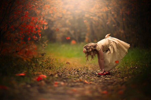 Fille en robe au milieu des feuilles qui tombent