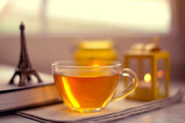 El reflejo del sol en una taza de té y junto a la estatuilla de la torre Eiffel