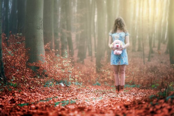 Girl with a plush pink dog in the woods