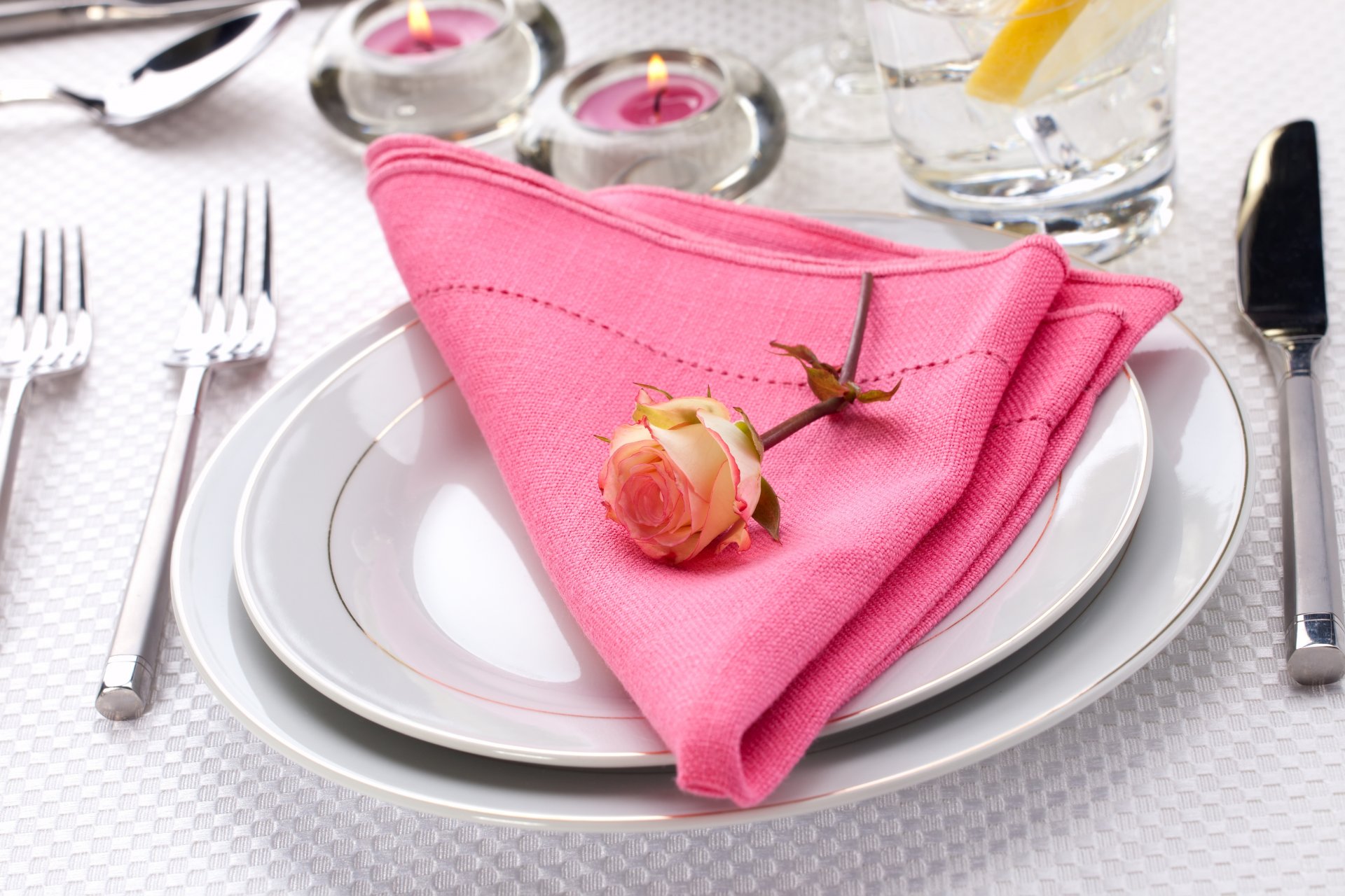 table service assiettes serviette fleur rose bougies couteau fourchettes