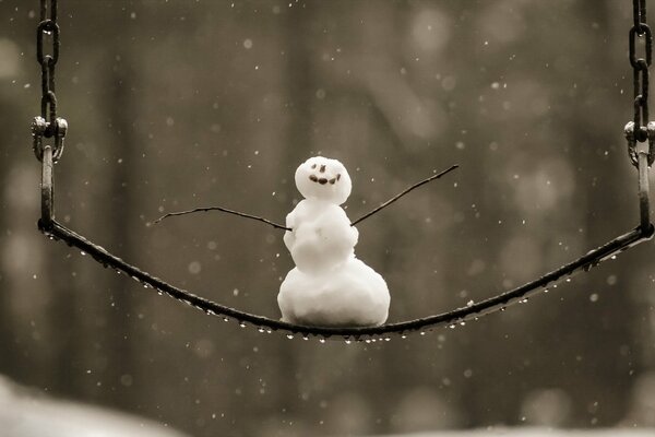 Joyeux petit bonhomme de neige sur une balançoire