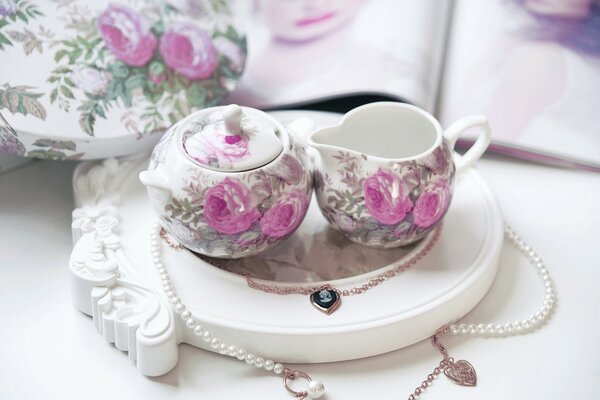 Tea set with roses and necklace on a white background