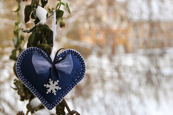 Corazón azul con copo de nieve sobre fondo de invierno