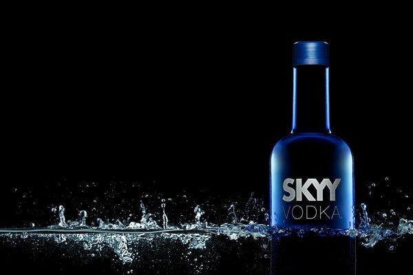 Skyy vodka on a black background with water drops