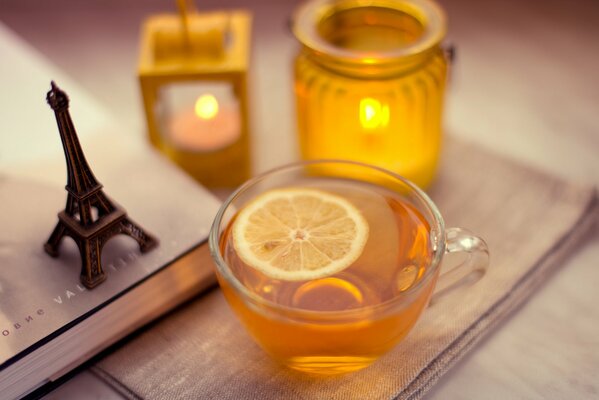 Sobre la mesa hay una taza de té con limón de la torre Eiffel y velas