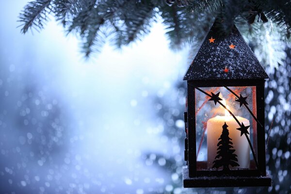 Lantern with candles on the background of a winter Christmas tree