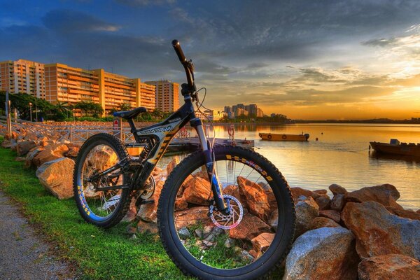 La bicicleta se encuentra en la orilla del río en medio de la puesta de sol