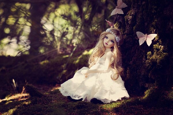 Poupée dans la forêt avec des papillons dans une belle robe blanche