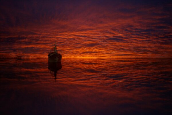 Schiff und Wolken im Spiegelbild bei Sonnenuntergang