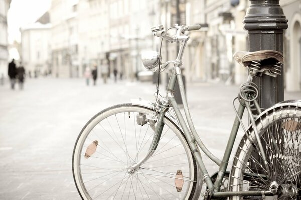 Велосипед опертый на столб улица прохожие