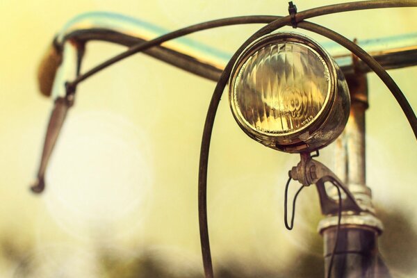 On a blurry background, a bicycle handlebar with a flashlight