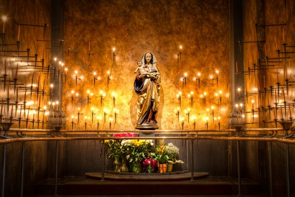 Statue de la vierge Marie en fleurs et bougies