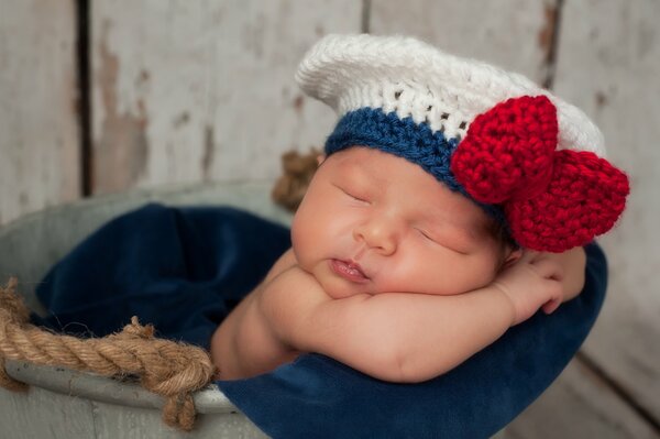 Enfant dans un béret tricoté avec un arc rouge