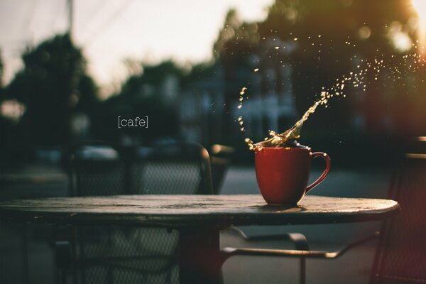 Un chapoteo de café en una taza en la mesa de un café al aire libre