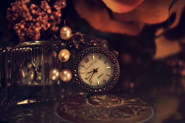 Hermoso reloj de metal con cuentas en la mesa con flores