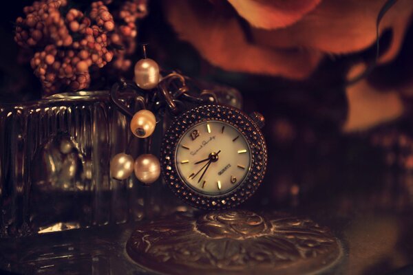 Piękny metalowy zegar z koralikami na stole z kwiatami