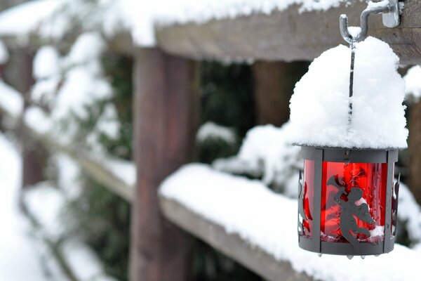 Linterna con un ángel en una cerca cubierta de nieve