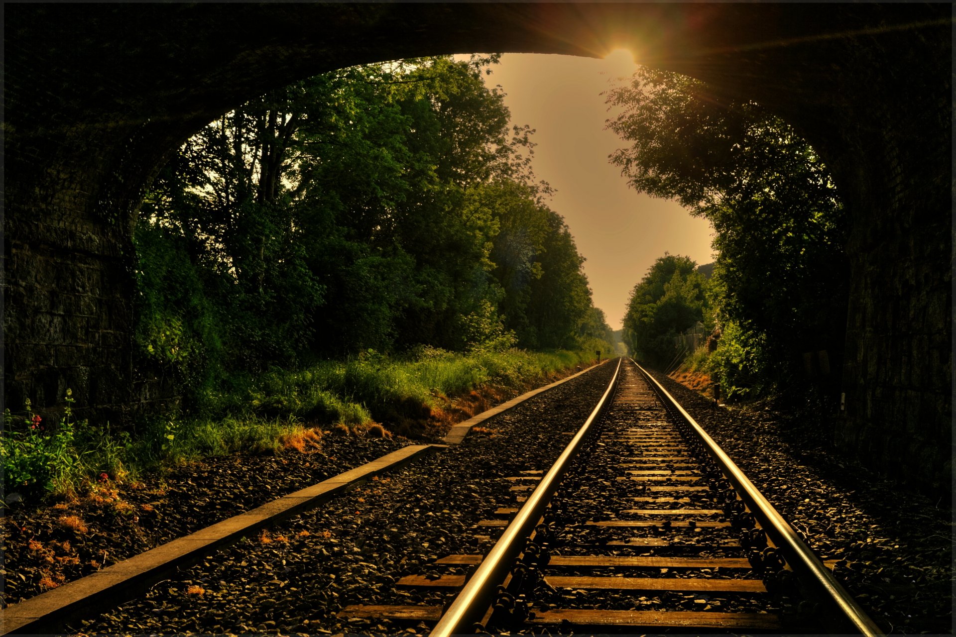 ferrocarril carretera rieles durmientes escombros bandeja arco puente árboles sol rayos