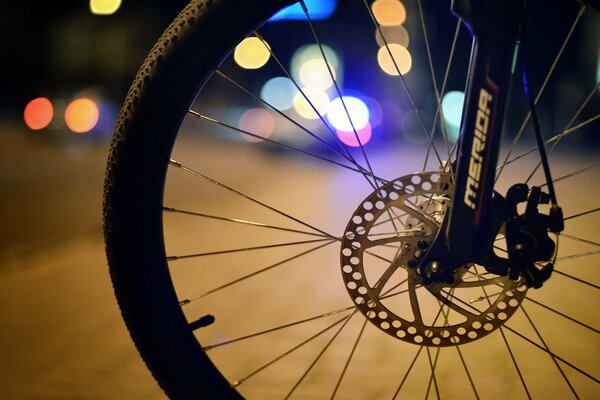 Bicycle wheel on a background of multicolored lights