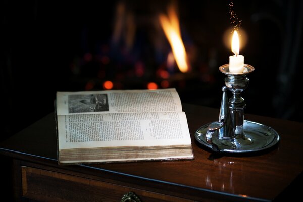 En el gabinete hay una vela en un candelero y un libro abierto