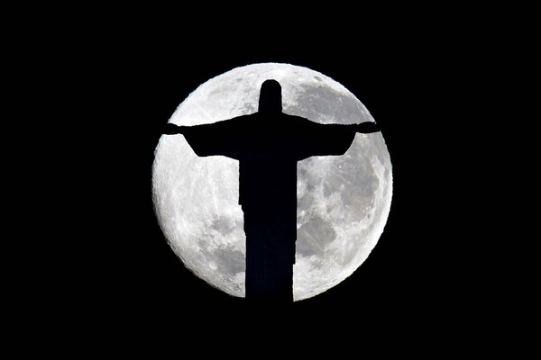 Statue of Christ the Saviour in Brazil at midnight on the background of a full moon