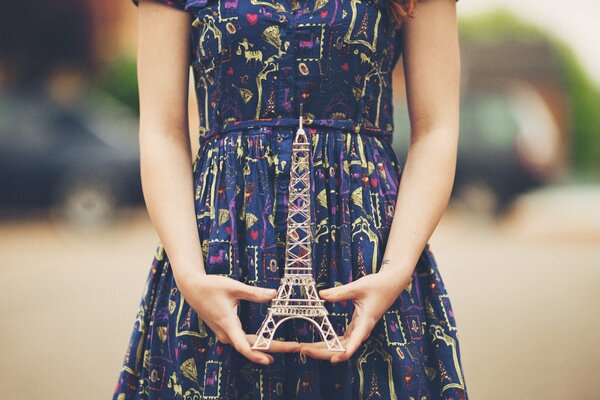 A girl holds a model of the Eiffel Tower in her hands