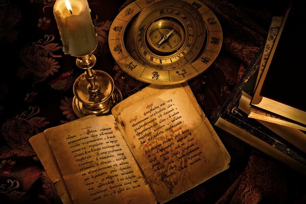 An old book with a compass by the candle on the table wallpaper