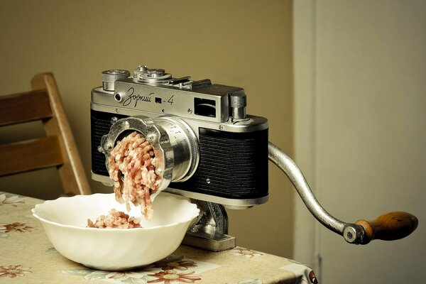 A meat grinder in the form of a photo apparatus on the background of a wall