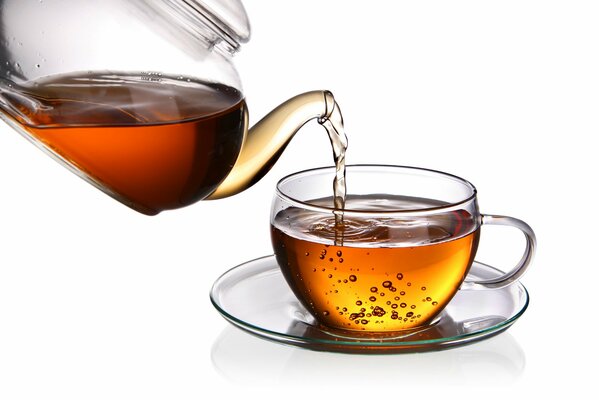 A glass transparent teapot with tea fills a glass transparent mug