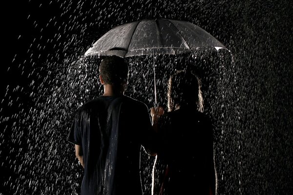 Couple d amoureux debout sous la pluie sous un parapluie