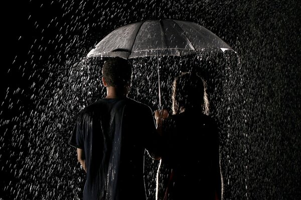Para kochanków stoi w deszczu pod parasolem