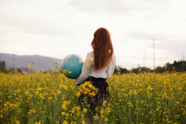 Foto de una chica pelirroja con un globo en sus manos en un campo de violación