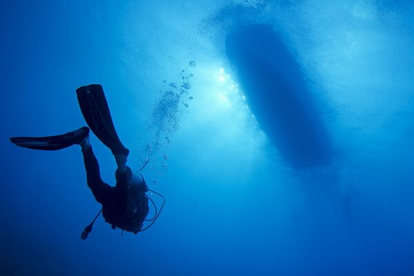 Scuba divers swim deep under the boat