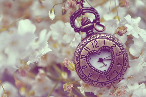 Reloj de bolsillo con corazón sobre fondo de flores