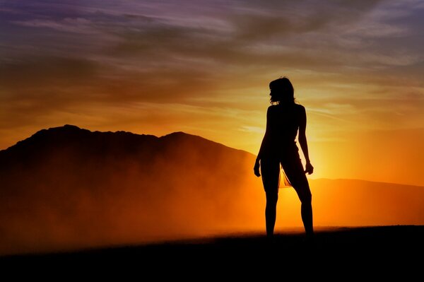 Belle silhouette de jeune fille sur fond de coucher de soleil et de montagnes